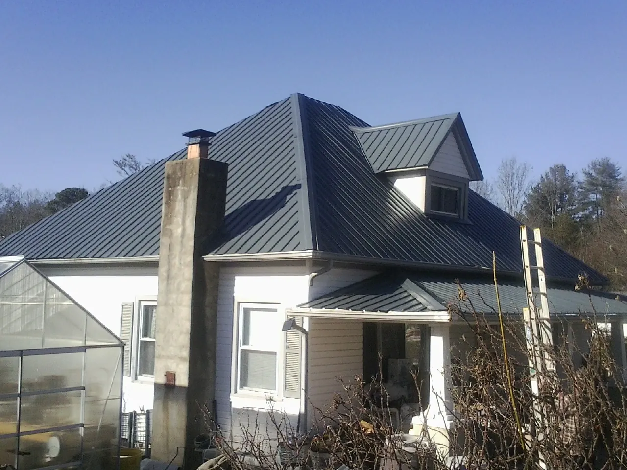 Dark blue standing seam metal roof on a white farmhouse with dormer — Slate & Tile Roof Repair by Roofing Brothers in Pacolet