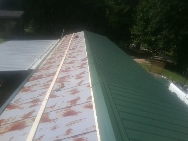 Old rusted panels beside newly installed green metal roofing — Wind Damage Roof Repair by Roofing Brothers in Pacolet
