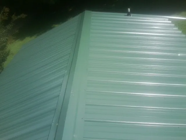 New green metal panels meeting at the ridge of a roof — Flat Roof Repair work by our crew in Pacolet