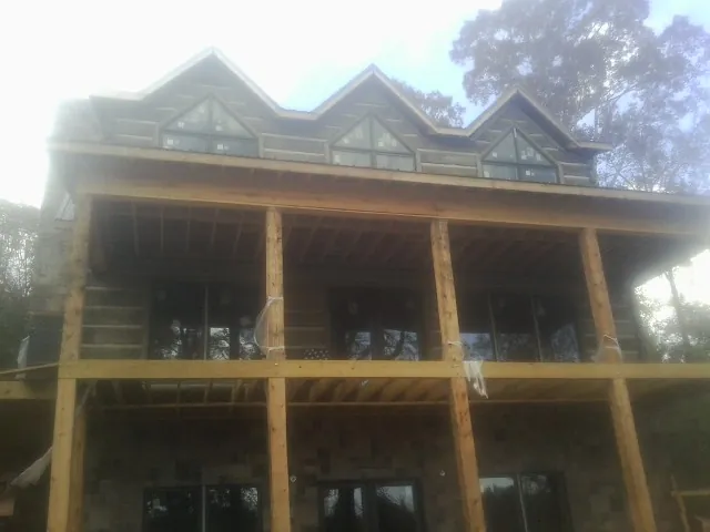 Dormers and porch framing on a large log home under construction — Roof Coating work by our crew in Pacolet