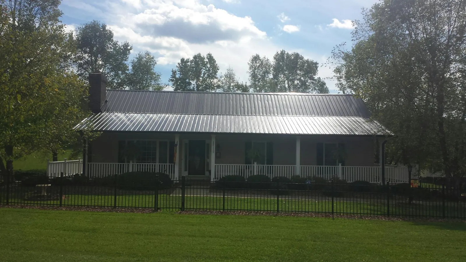 Gray metal roof on a brick ranch with a full width front porch — Gutter Guard Installation work by our crew in Pacolet