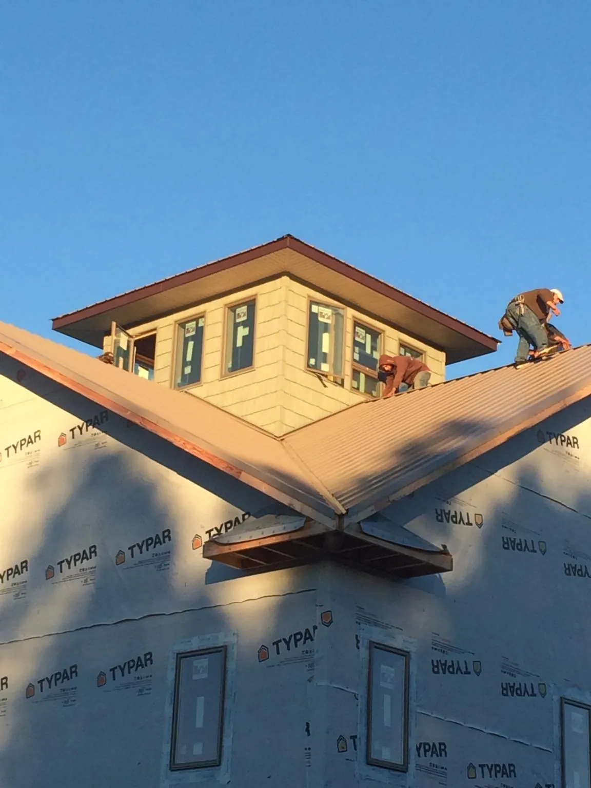 Roofers working around a rooftop cupola on a new metal roof at sunset — Roof Waterproofing in Pacolet by Roofing Brothers